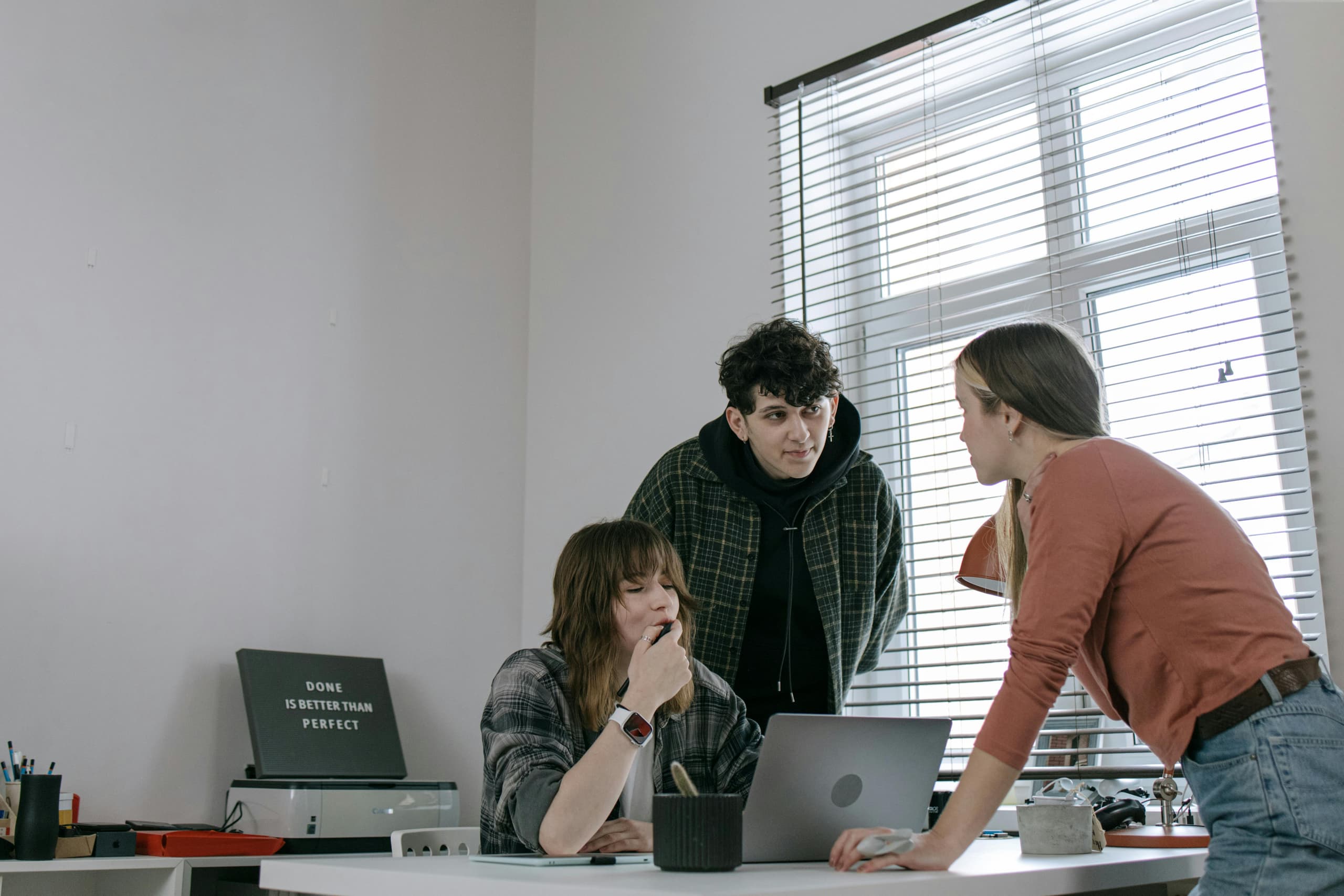 Development team collaborating around a laptop in a bright office—developer outsourcing and dedicated squads