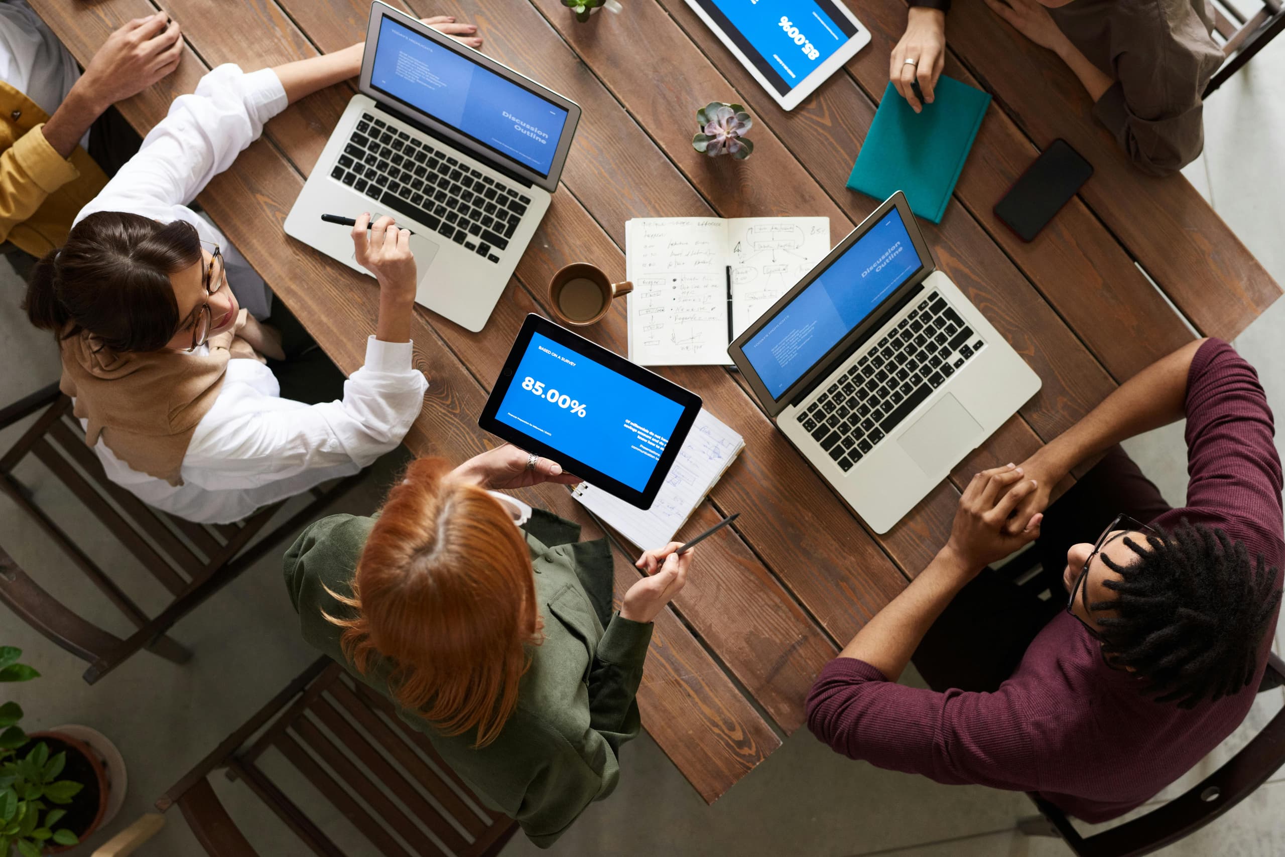 Business consulting team collaborating around a table with laptops and notes